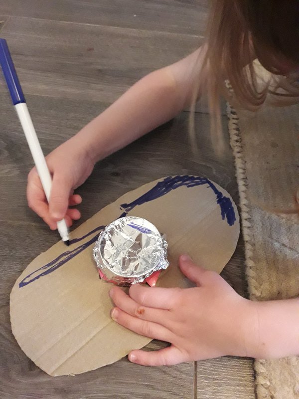 Child decorating cardboard shield using colouring pen