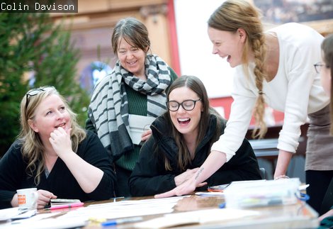 Four people around a table laughing. 