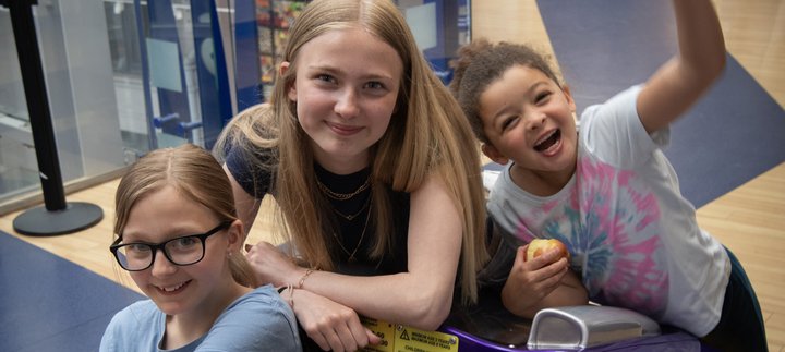 Three girls of various age sitting having fun in the museum 