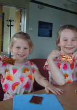 Two young girls holding up the objects they've made
