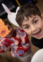 two children hold up their creations and smile