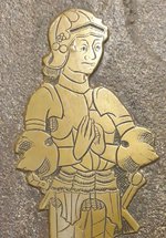 A gold plaque of a character dressed in armour on a brick wall 
