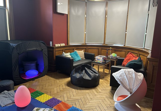 A room with soft furnishings and sensory toys and mats out on a wooden floor 