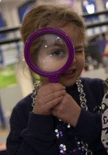Two girls peer through magnifying glasses