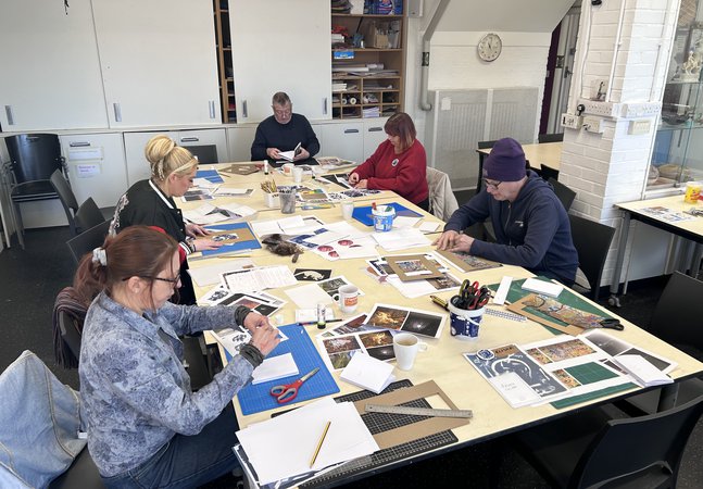 A group of adults sat around a large table, taking part in a craft activity together.
