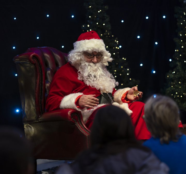 Children sat in front of a seating Santa as he reads to them at Woodhorn Museum