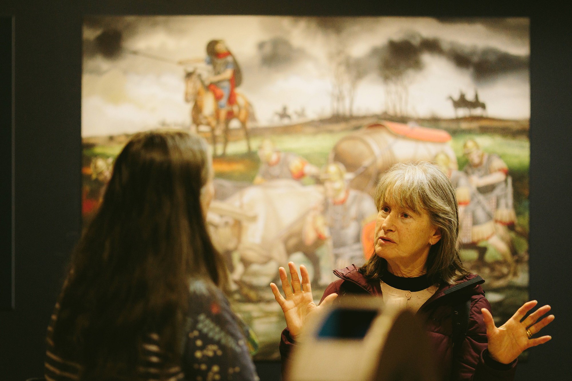 Two women having a social conversation at a museum.