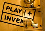 Image of wooden panel stamped with PLAY + INVENT