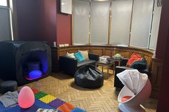 A room with soft furnishings and sensory toys and mats out on a wooden floor 