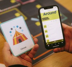 A mobile phone with a game app and a board game with cards with pictures on them