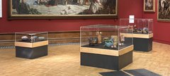 Three glass display cases with ceramic objects in a art gallery.