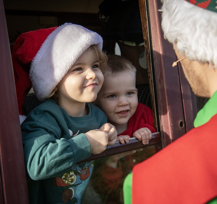 Elf Express child looking at an elf through the window of a train carriage