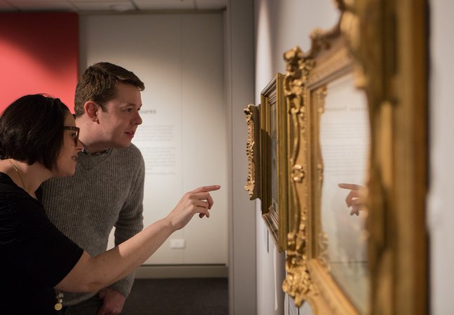 People look at paintings in the gallery