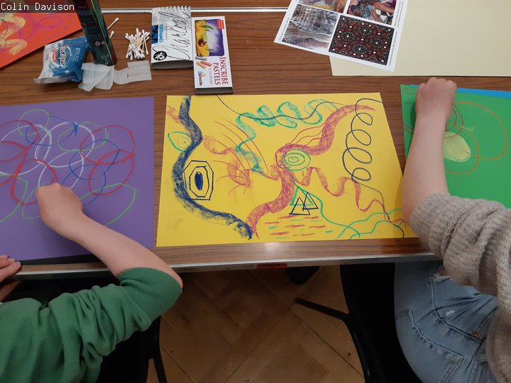 Two young people creating art using pastels