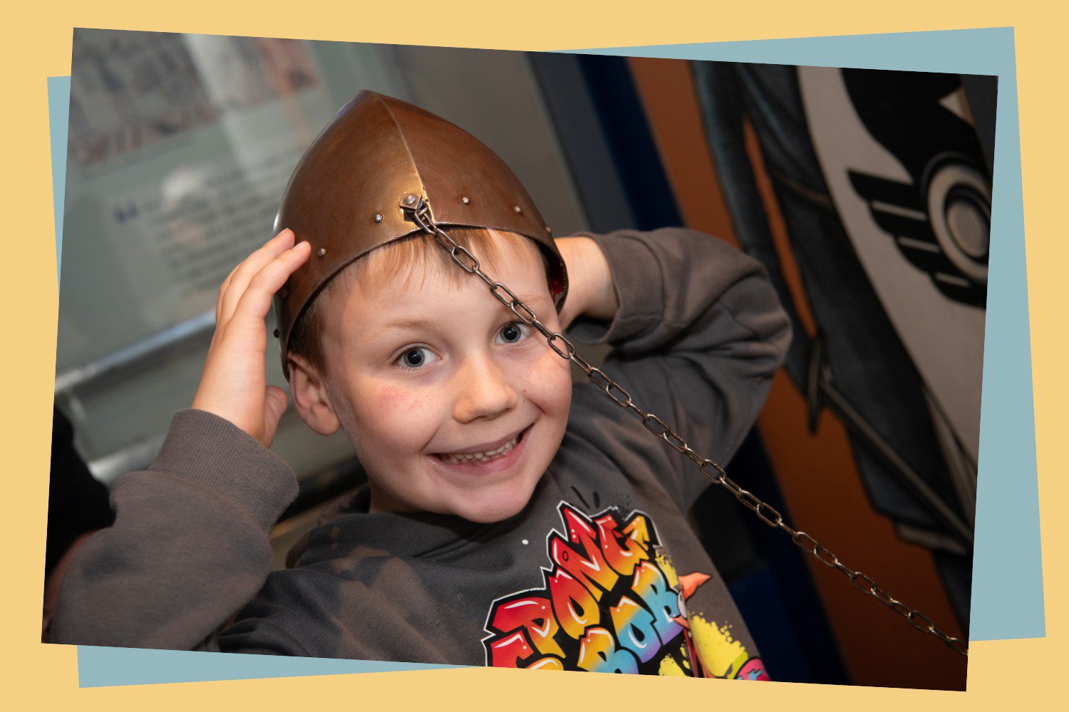 A boy playing with a helmet in a museum.