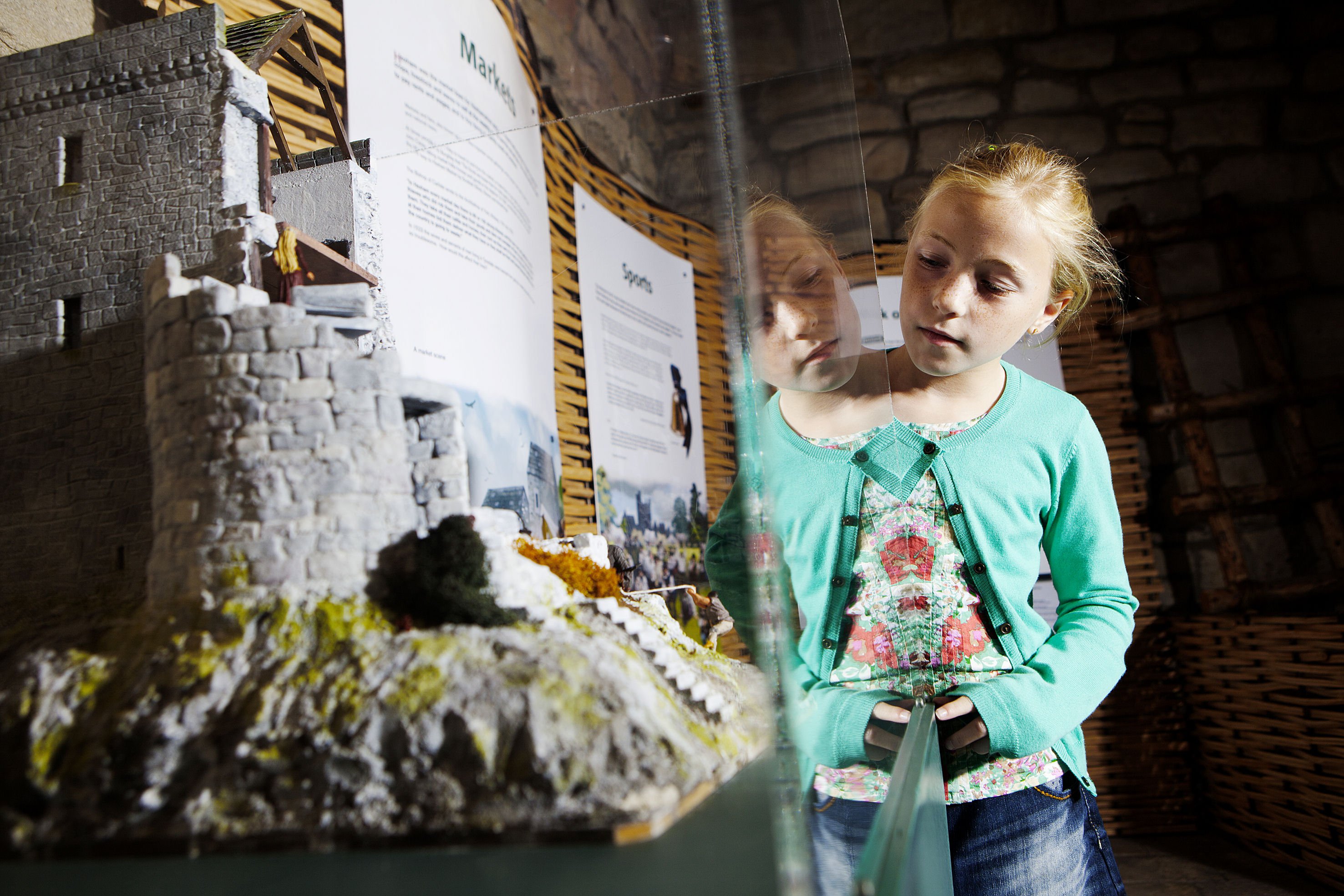 A child looks at a model of an old building in a glass case