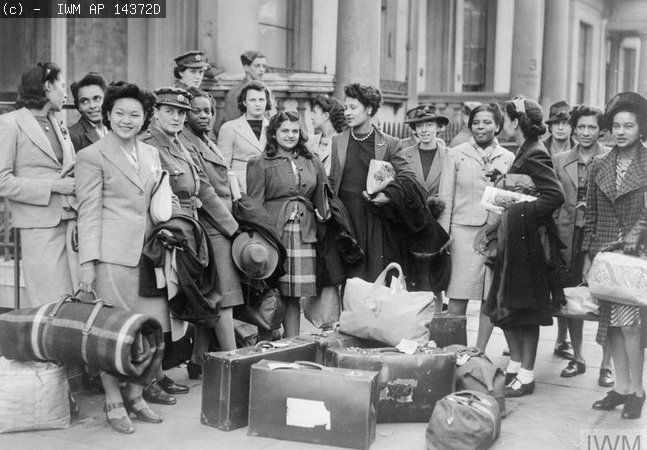 A group of West Indian women recruited to join the ATS, wait for transport to take them to their train© IWM AP 14372D