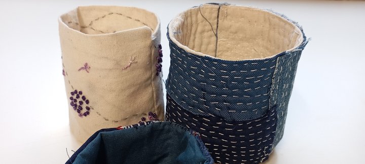 Three hand embroidered fabric round containers in blue and cream