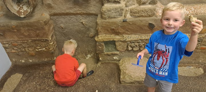 Two boys in Time Quest - 1 is digging and 1 is holding up an object,