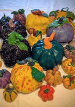 A colourful array of painted ceramic pumpkins on a white table cloth.