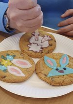 A photograph of someone decorating cookies with a spring theme, including bunnies and flowers.