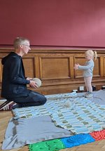 An adult and child throwing a ball to each other in a play space.