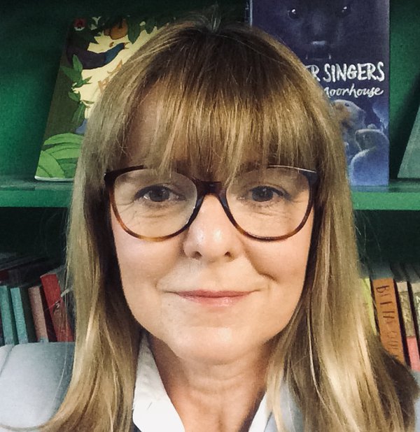 A person with light brown hair, wearing dark rimmed glasses, looking at the camera. A person with light brown hair, wearing dark rimmed glasses, looking at the camera.
