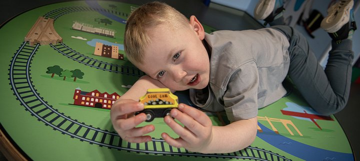 boy holds toy train in gallery