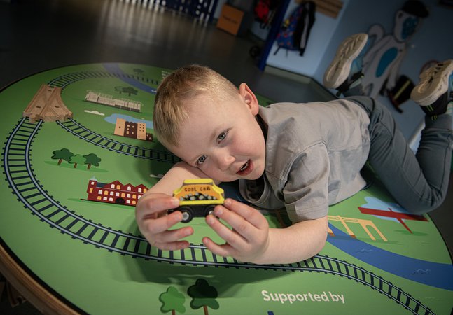 boy holds toy train in gallery