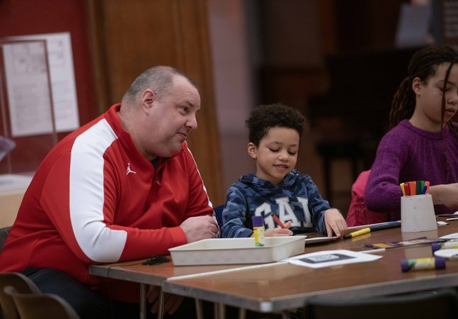 An adult and child sat at a table drawing together.