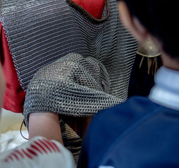 Replica chain mail tunic being worn by a child while two other children inspect the tunic