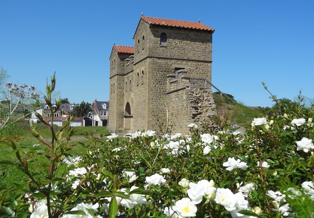 White rose bushes with Roman style gatehouse in the background