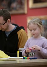 An adult and child sat a table with craft materials.