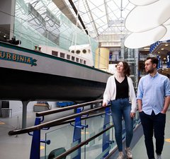 Two young adults walk alongside Turbinia