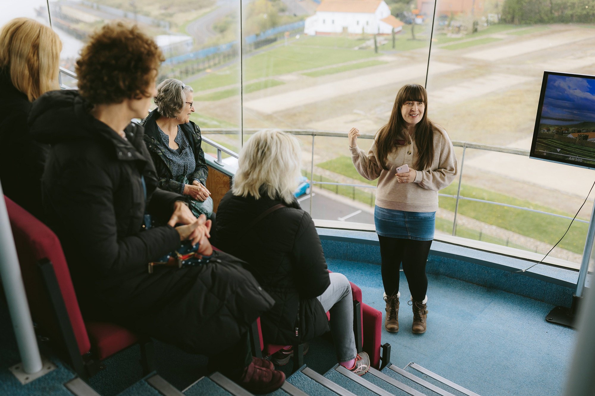 Woman leading an outreach session in a viewing tower above ruins of a Roman fort.
