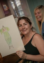 a woman holds up her sketch of a vinatge dress