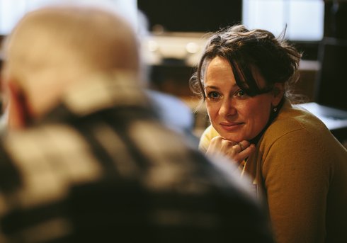 A woman looking on as she listens to a conversation.