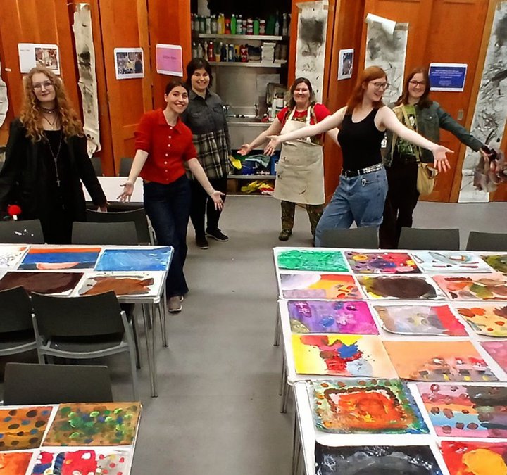 A group of young people standing behind work they've made.