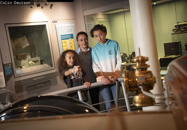 A mum, daughter and son look at objects in the gallery