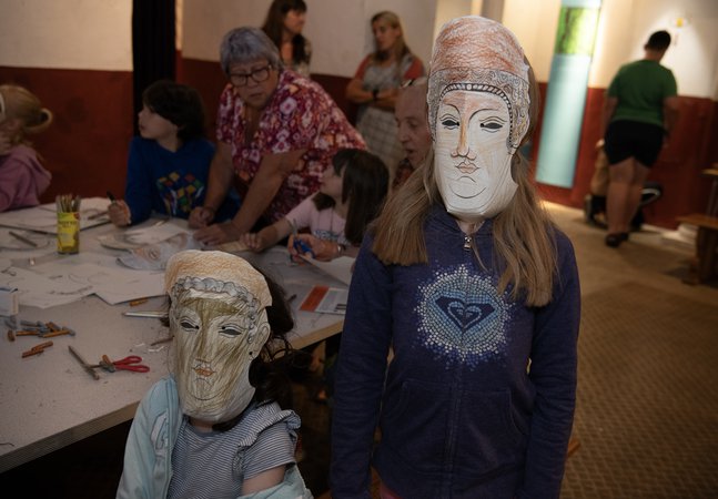 Two children in a Roman museum gallery wearing replica card cavalry masks
