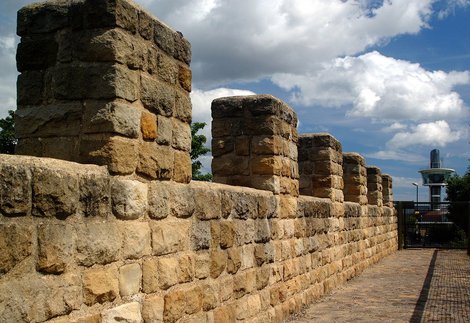 Modern reconstruction of Hadrian's Wall with Segedunum Roman Fort viewing tower in background