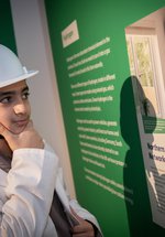 boy in hard hat looks panel thoughtfuly