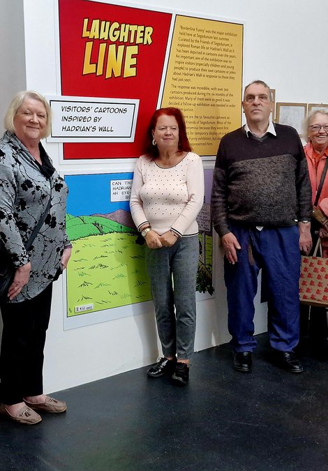 Group of people standing next to an exhibition of drawings and cartoons