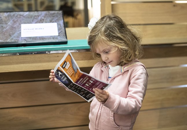 A young girl in a museum looking at a worksheet.
