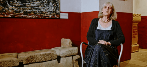 Female curator sat in a gallery next to Roman stone toilets