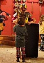 Roman solider holding a spear and shield in Shrine of the Standards talking to a young boy
