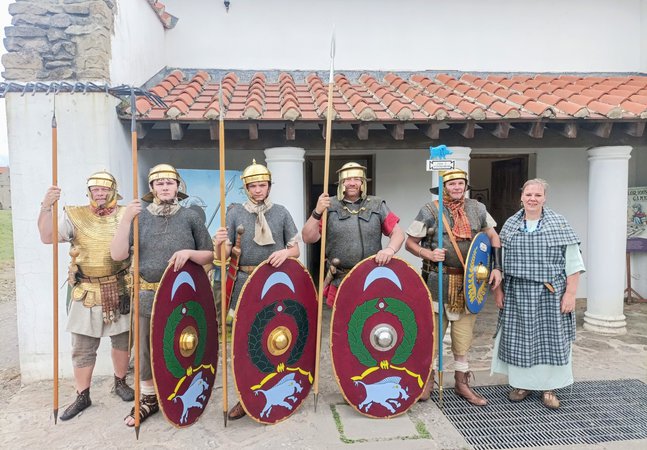 The Tungrian re-enactment group in replica Roman costumes outside the reconstructed buildings