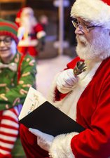 Santa reads a story as an elf listens