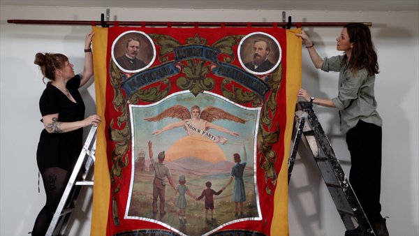 Woodhorn team carefully hanging a mining banner for restoration