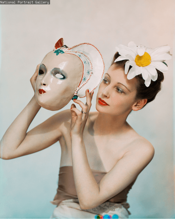 A woman holding a mask on a pale background